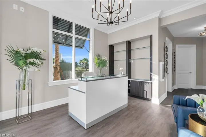 Kitchen with ornamental molding, dark wood-style flooring, a kitchen island, and baseboards