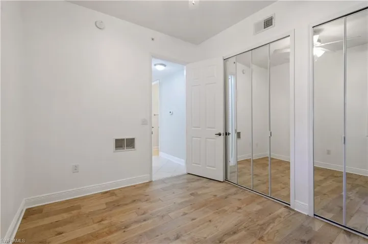 Unfurnished bedroom featuring visible vents, light wood-style flooring, two closets, and baseboards