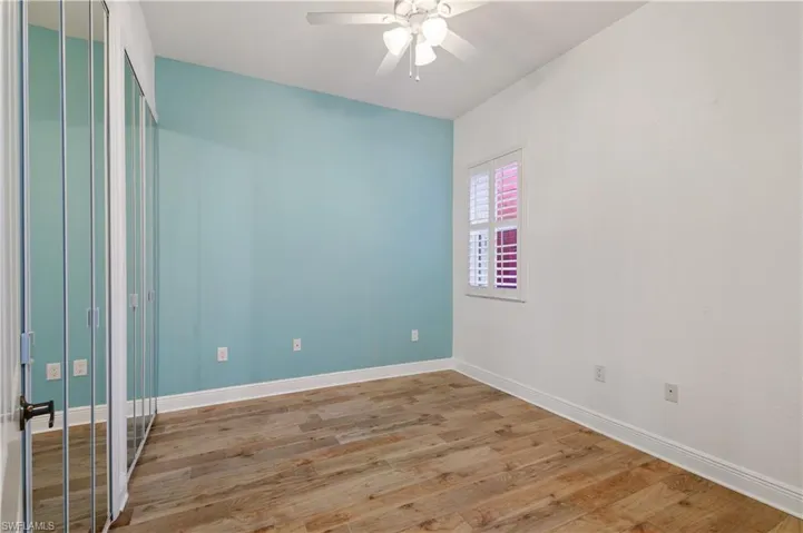 Guest room with baseboards, light wood-type flooring, and ceiling fan