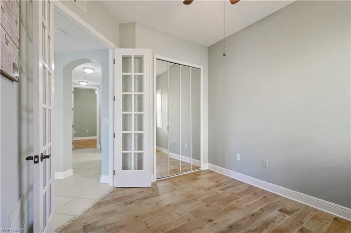 Unfurnished bedroom with arched walkways, light wood-style flooring, a closet, and baseboards