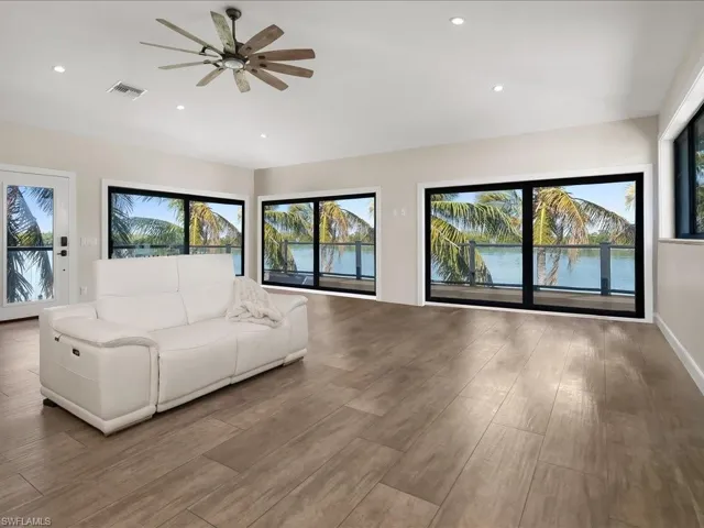 Living room featuring ceiling fan, a water view, recessed lighting, and wood finished floors