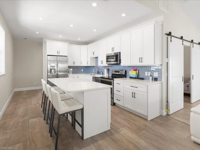 Kitchen with a barn door, white cabinetry, stainless steel appliances, a breakfast bar area, and a kitchen island