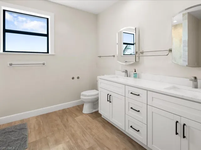Full bath with double vanity and light wood-style floors
