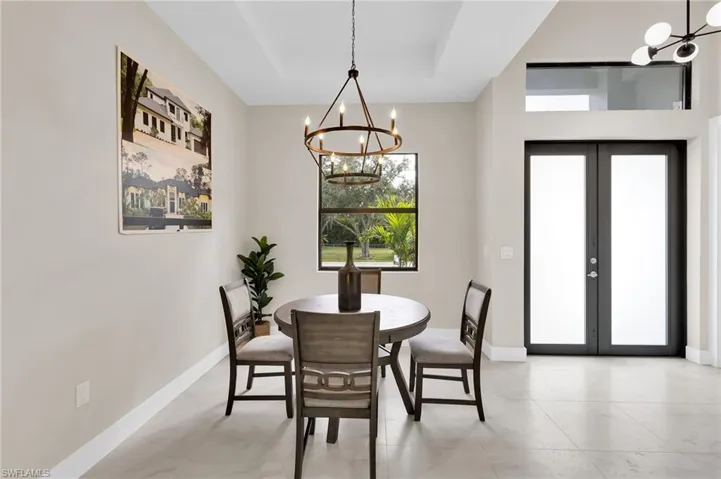 Dining room featuring a chandelier, french doors, and a raised ceiling