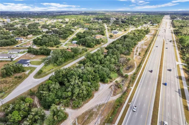 Aerial view of property and surrounding area featuring a highway and a tree filled landscape