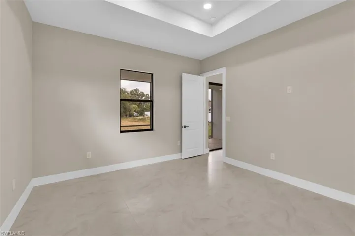 Spare room featuring a tray ceiling, recessed lighting, and light marble finish flooring