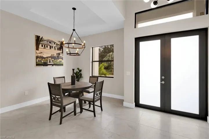 Dining space featuring a tray ceiling, a chandelier, and french doors