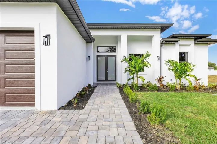 View of exterior entry with stucco siding and a lawn