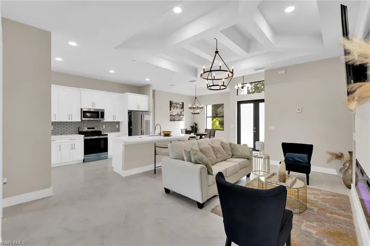 Living area featuring beamed ceiling, recessed lighting, a chandelier, and french doors
