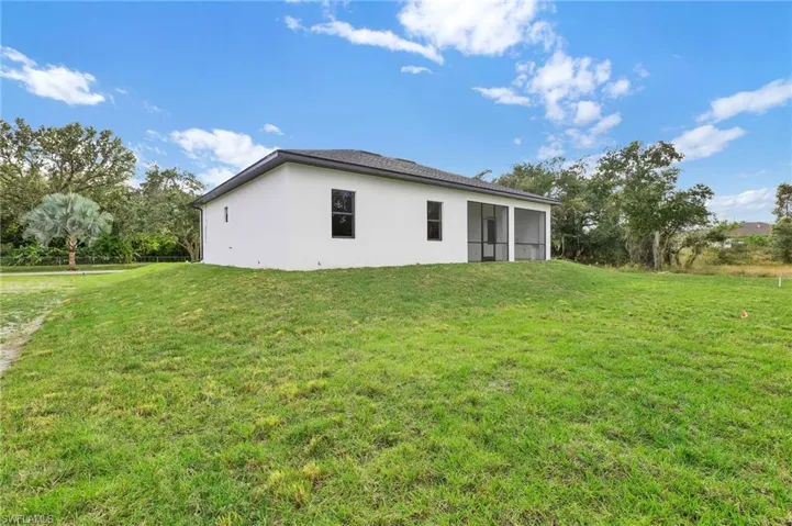 View of property exterior featuring a yard, a sunroom, and stucco siding