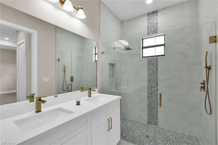 Bathroom with a marble finish shower, double vanity, and recessed lighting
