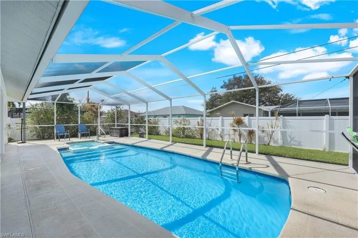 View of pool with a patio, glass enclosure, and an in ground hot tub