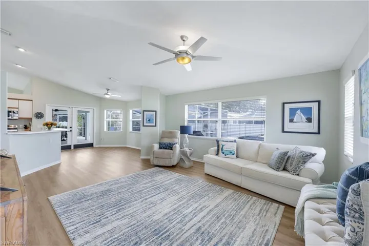 Living room with french doors, lofted ceiling, plenty of natural light, and light hardwood / wood-style flooring