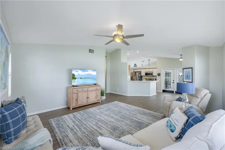 Living room featuring french doors, lofted ceiling, dark hardwood / wood-style floors, ceiling fan, and a healthy amount of sunlight