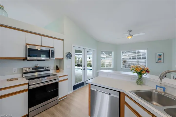 Kitchen with french doors, sink, white cabinetry, light hardwood / wood-style flooring, and appliances with stainless steel finishes