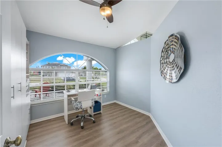 Home office with hardwood / wood-style flooring, ceiling fan, and lofted ceiling