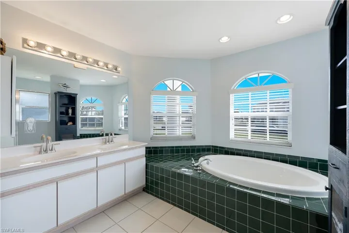Bathroom with vanity, tiled tub, and tile patterned floors