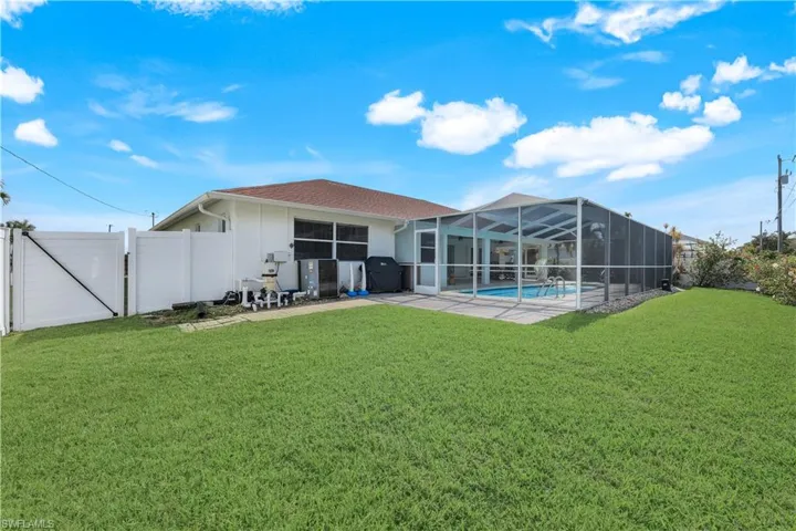 Rear view of house with a fenced in pool, a yard, and glass enclosure
