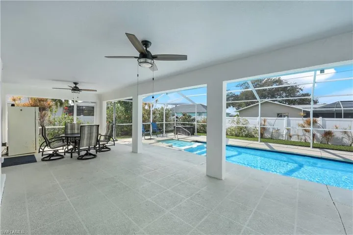 View of pool with a lanai, a jacuzzi, ceiling fan, and a patio area