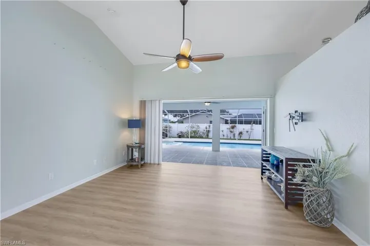 Living room with ceiling fan, lofted ceiling, and light hardwood / wood-style floors
