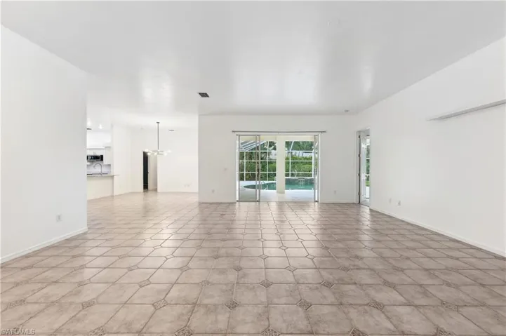 Unfurnished living room with a chandelier and baseboards