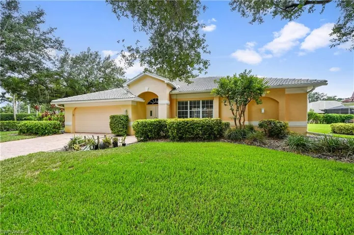 View of front of house with stucco siding, a tiled roof, a front yard, and an attached garage