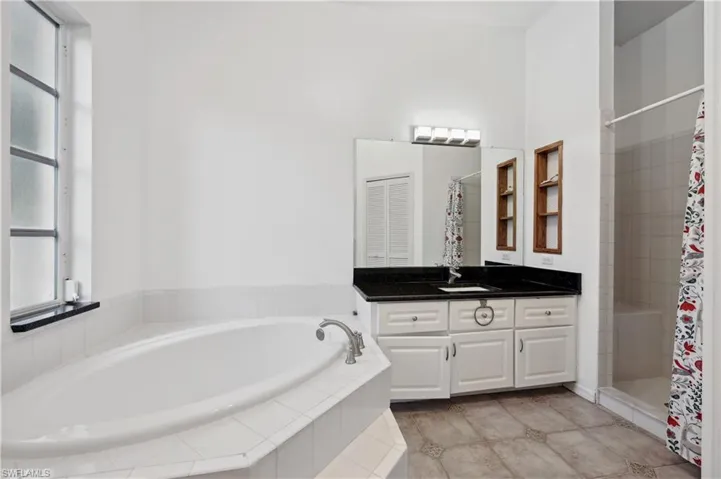 Bathroom with vanity, a stall shower, a garden tub, and light tile patterned floors