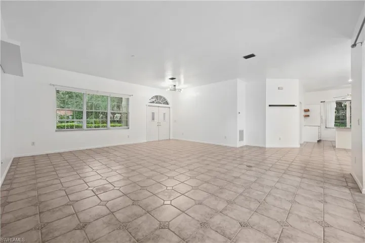 Unfurnished living room with baseboards and a chandelier