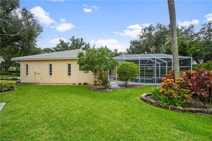 Rear view of house with a lanai, a lawn, stucco siding, a sunroom, and a tile roof