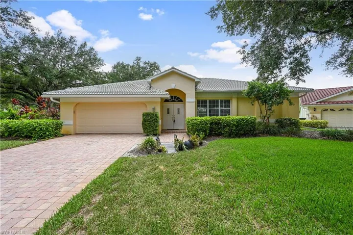 Single story home featuring stucco siding, a tiled roof, a front lawn, and decorative driveway