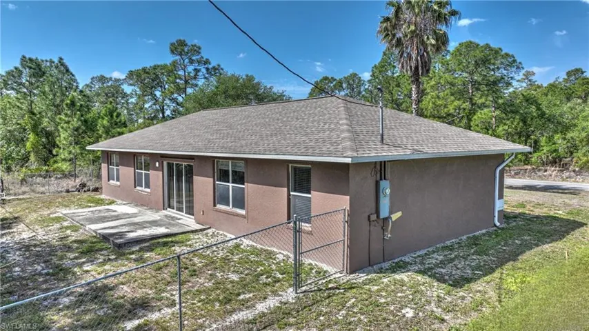 View of home's exterior with a patio area, a shingled roof, stucco siding, and fence
