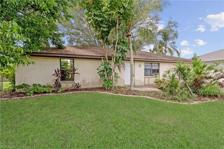 View of front of house with a front yard, stucco siding, and roof with shingles