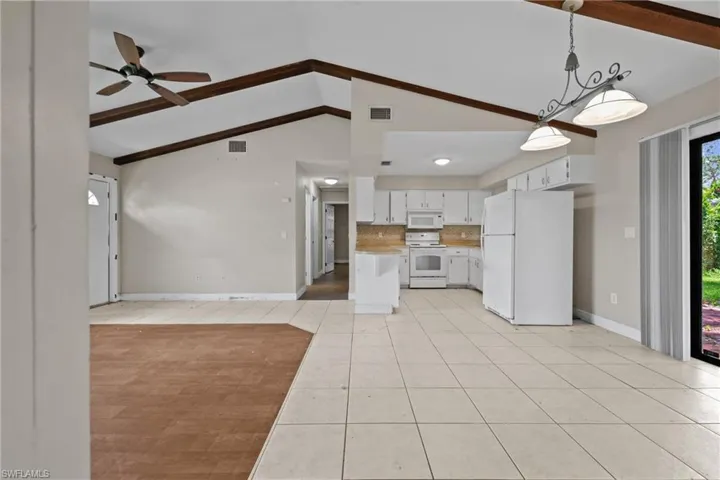 Kitchen featuring white appliances, light tile patterned floors, open floor plan, light countertops, and a ceiling fan