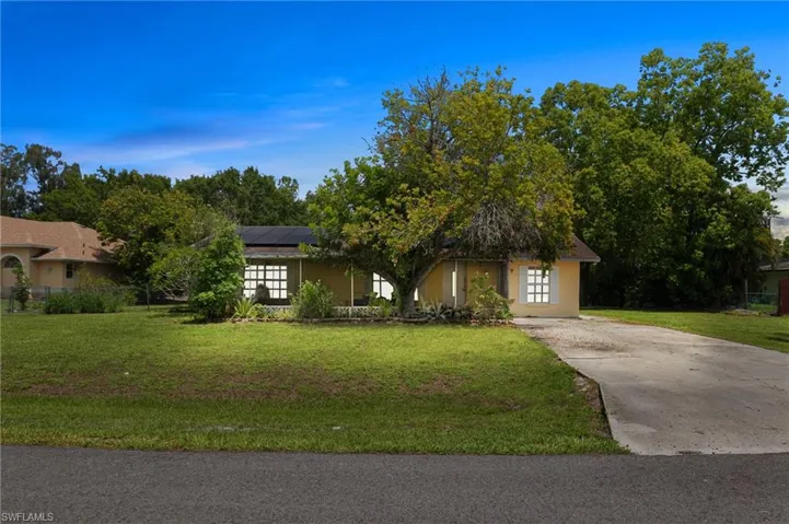 View of front of home featuring solar panels, a front yard, and stucco siding
