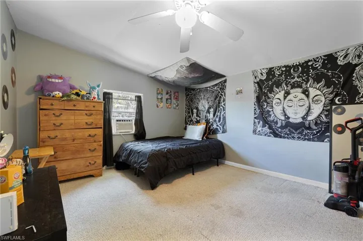 Carpeted bedroom with cooling unit, vaulted ceiling, and ceiling fan