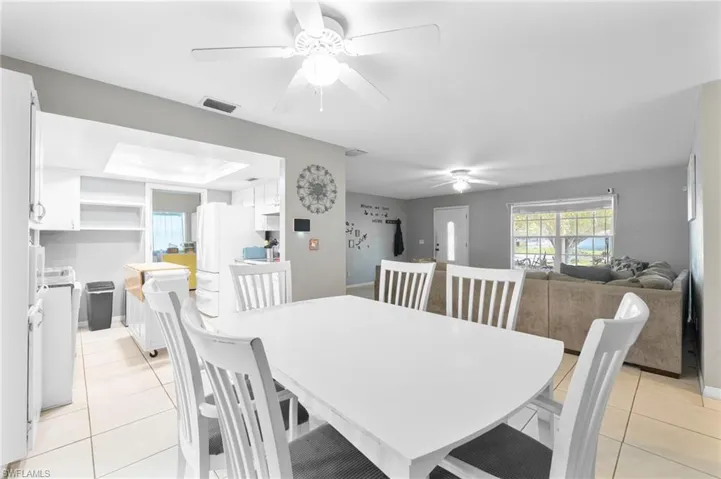 Dining area with ceiling fan, light tile patterned flooring, and a raised ceiling