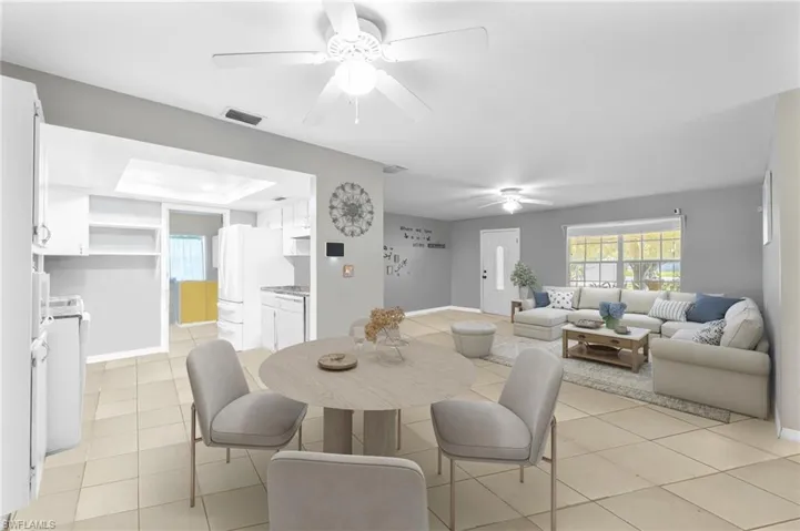 Dining room with a ceiling fan, light tile patterned floors, washer / clothes dryer, and a tray ceiling