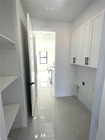 Laundry room with cabinets, sink, light tile flooring, and hookup for an electric dryer