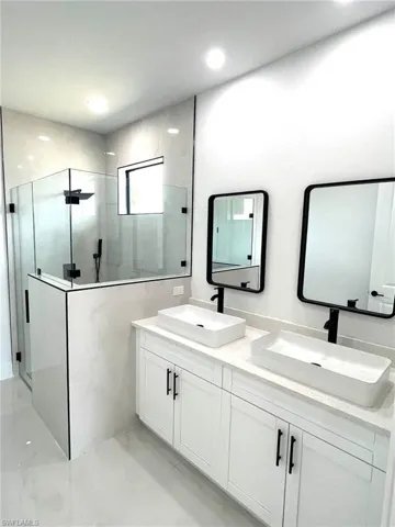 Bathroom featuring a tile shower and double sink vanity