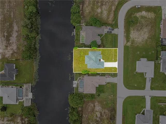 Aerial view of residential area with a nearby body of water and property boundaries highlighted