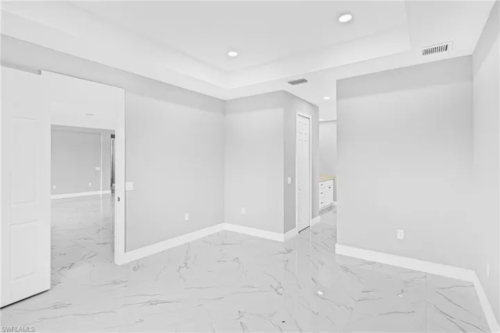 Spare room featuring light marble finish flooring, recessed lighting, and a tray ceiling