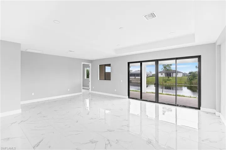 Unfurnished room featuring light marble finish flooring, a water view, and a tray ceiling