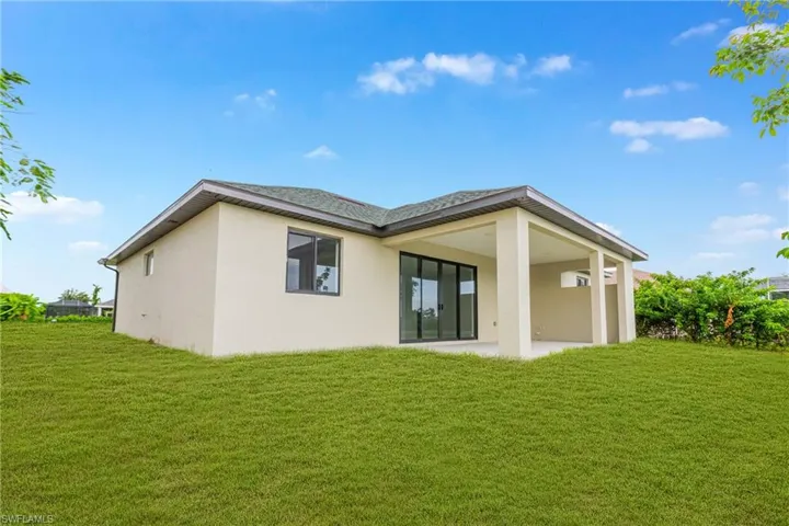 Back of property with stucco siding, a yard, and a patio area