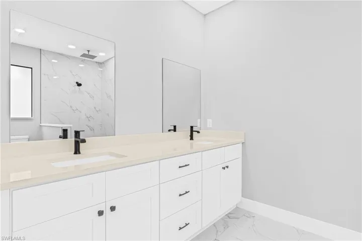 Full bath with light marble finish flooring, double vanity, and a marble finish shower