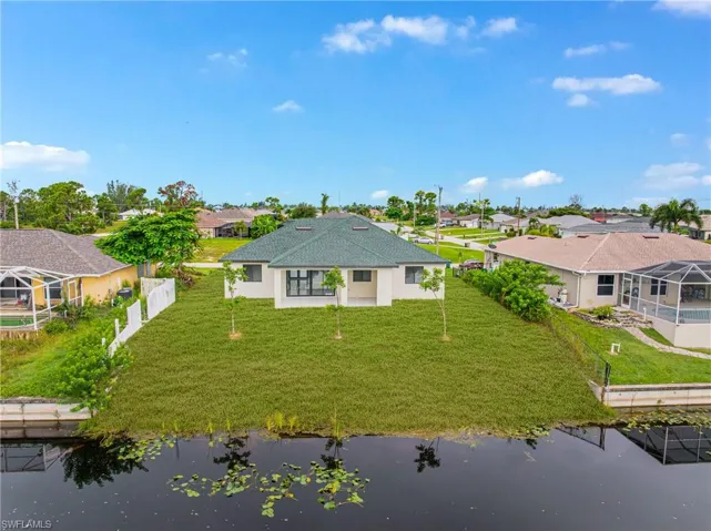 Back of property with a residential view, a water view, a sunroom, and a patio area