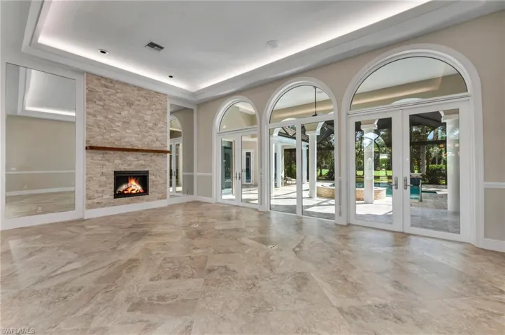 Unfurnished living room with a fireplace, french doors, and a raised ceiling
