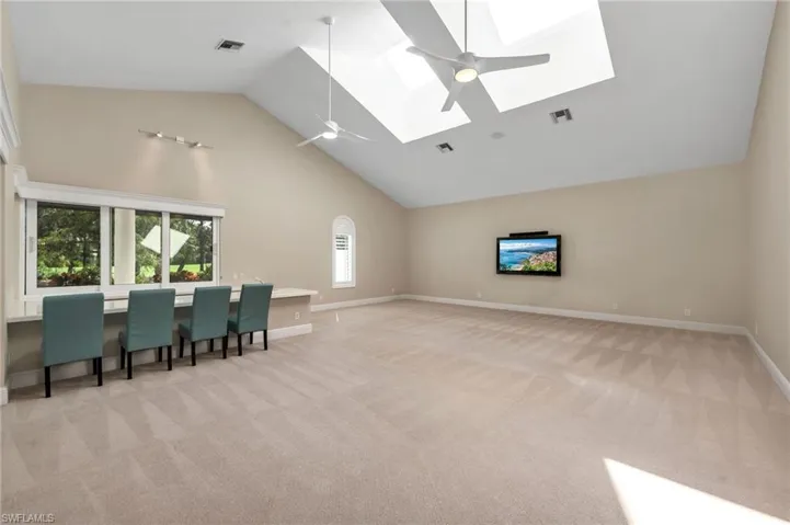 Living room with light carpet, a skylight, high vaulted ceiling, and  bar