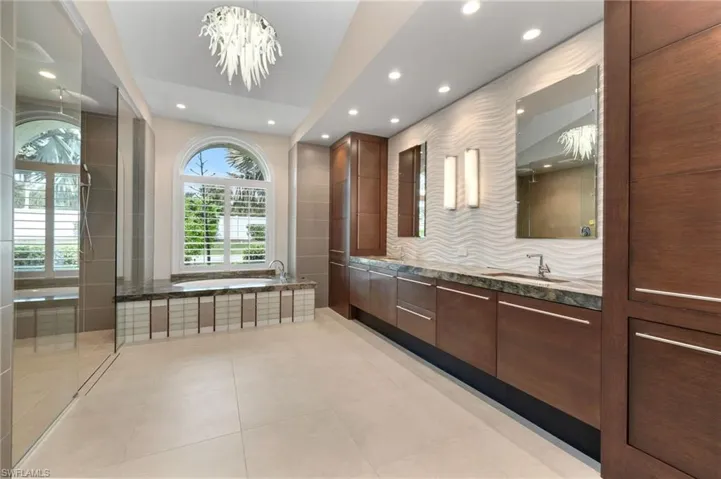 Primary Bath with tile patterned flooring, a bathtub, an inviting chandelier, and vanity