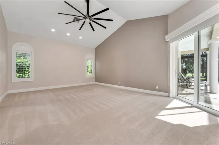 Primaary Bedroom featuring ceiling fan, high vaulted ceiling, a wealth of natural light, and light carpet