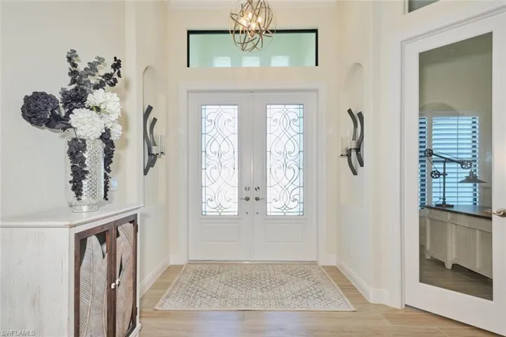 Entrance Foyer featuring Double etched doors, Recessed wall accent and Contemporary Chandelier. Glass entry door to Den
